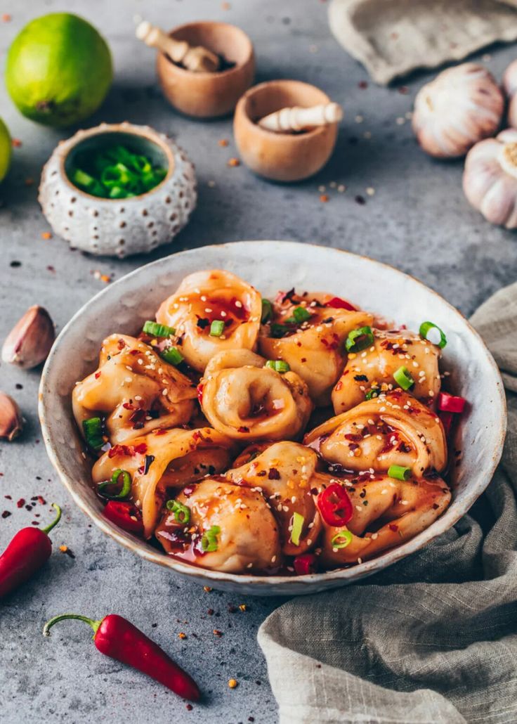 a white bowl filled with food on top of a table next to garlic and peppers