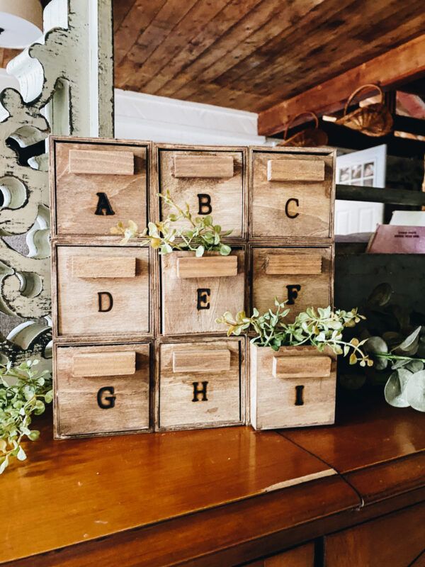 several wooden boxes with letters and plants in them sitting on a table next to a mirror