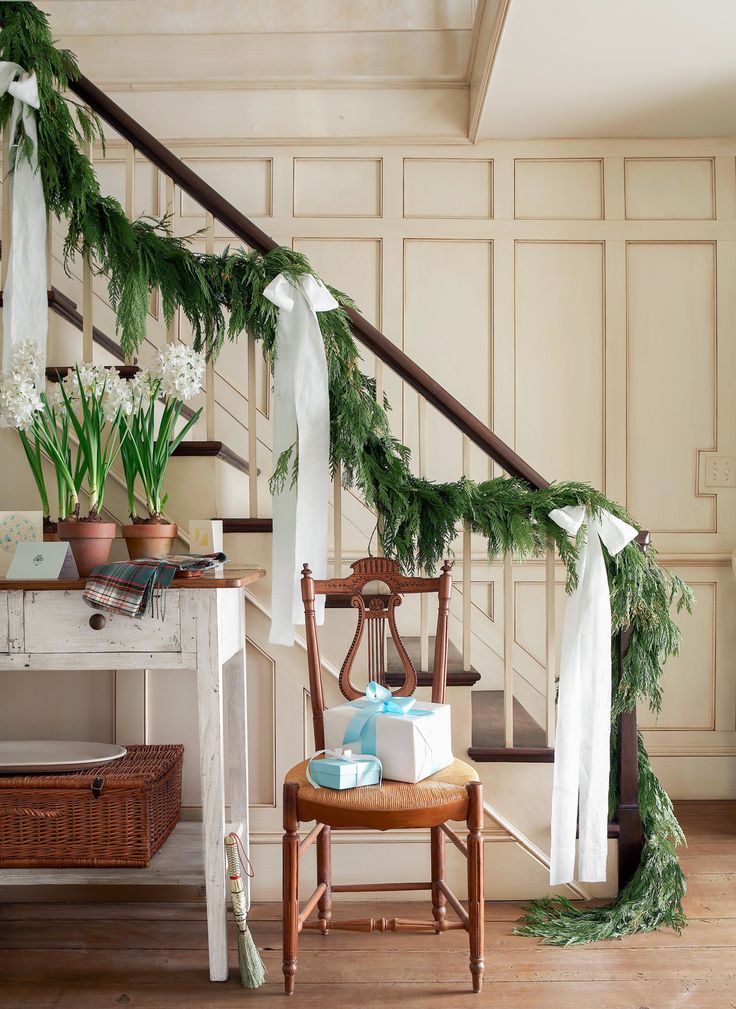 a staircase decorated for christmas with greenery and presents on the bannister rail