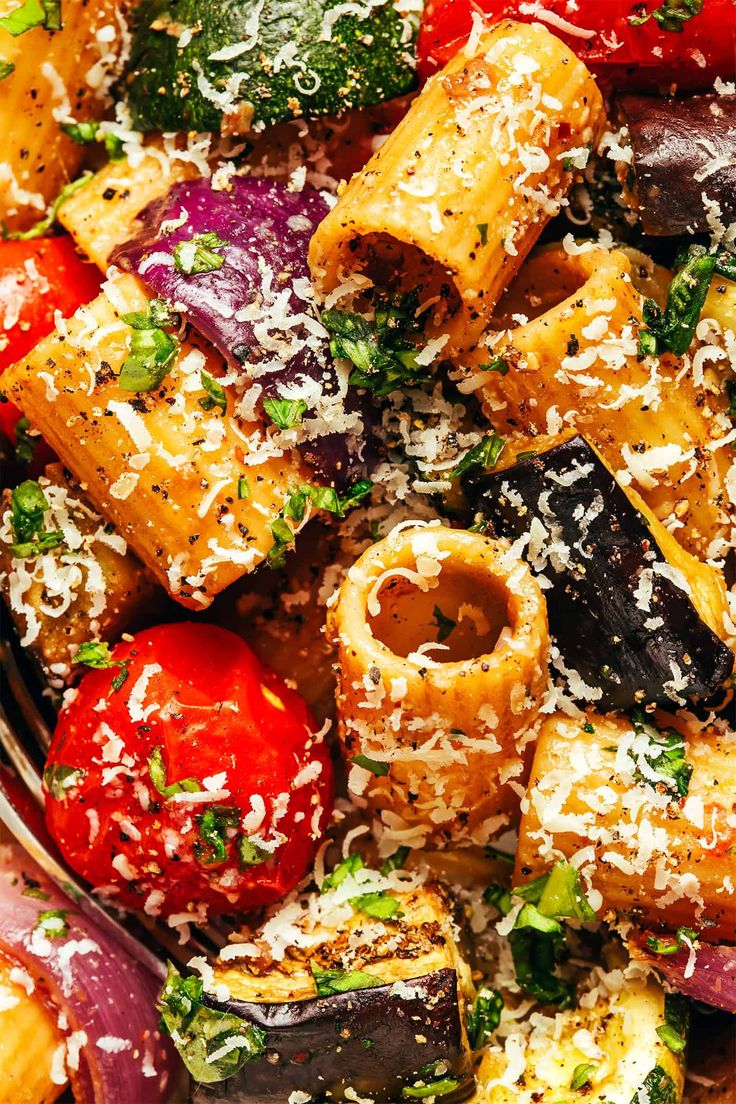 a bowl filled with pasta and vegetables covered in parmesan cheese