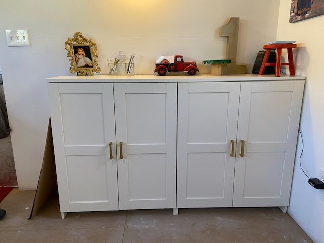 a white cabinet sitting in the corner of a room next to a red carpeted floor