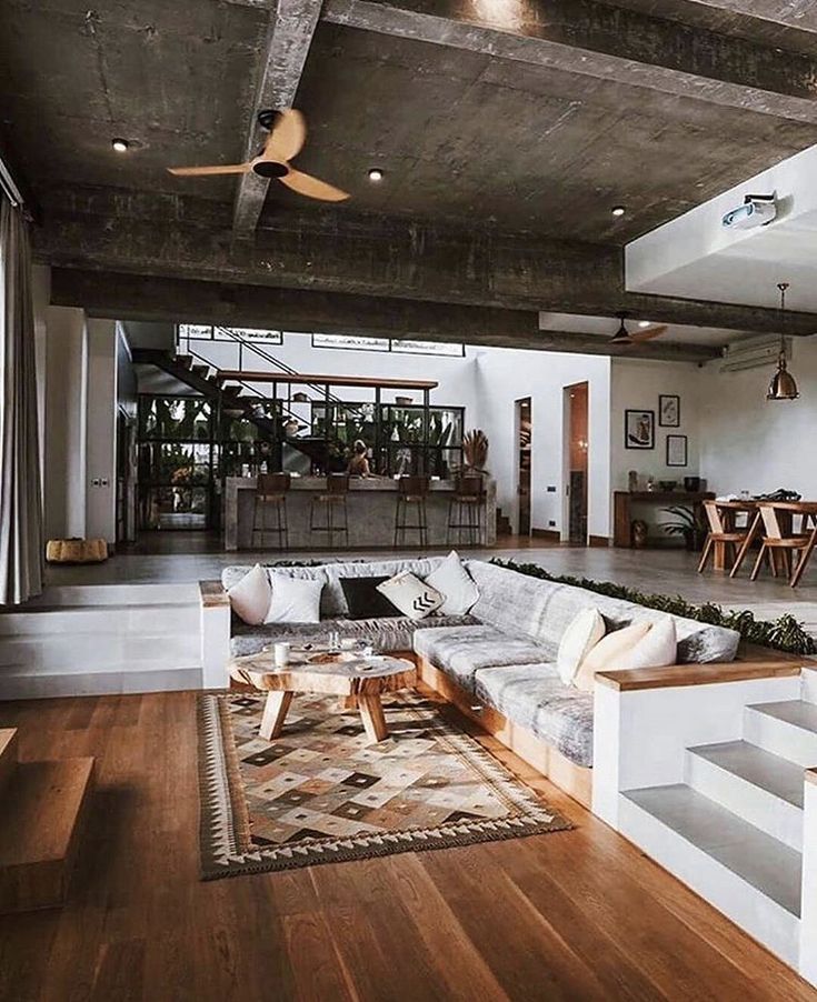 a living room filled with lots of furniture and a ceiling fan in the middle of it