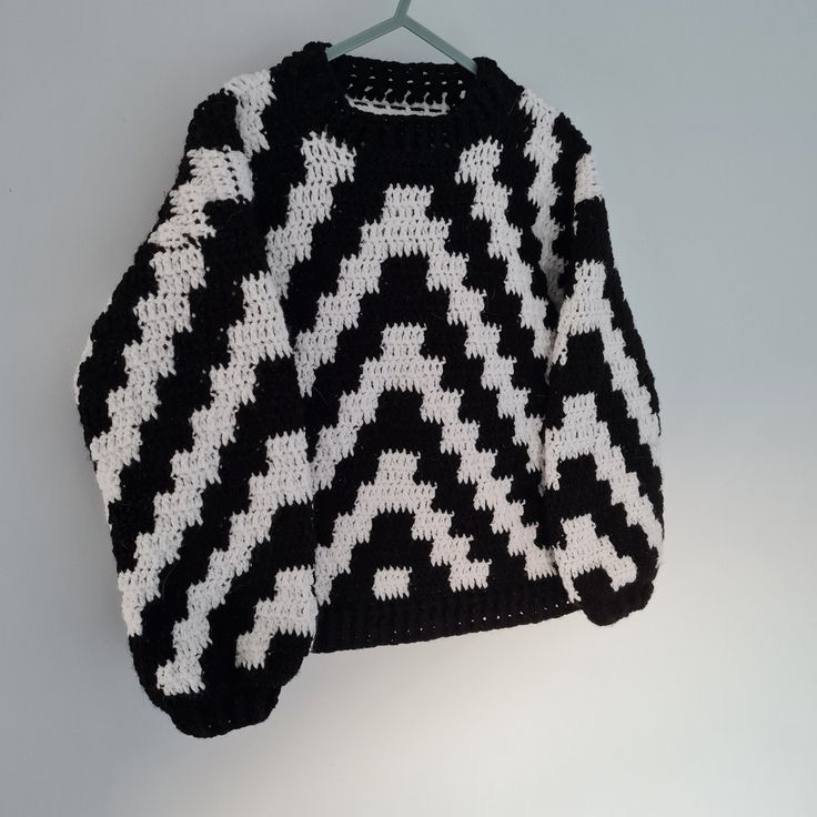 a black and white sweater hanging on a hanger with an object in the background