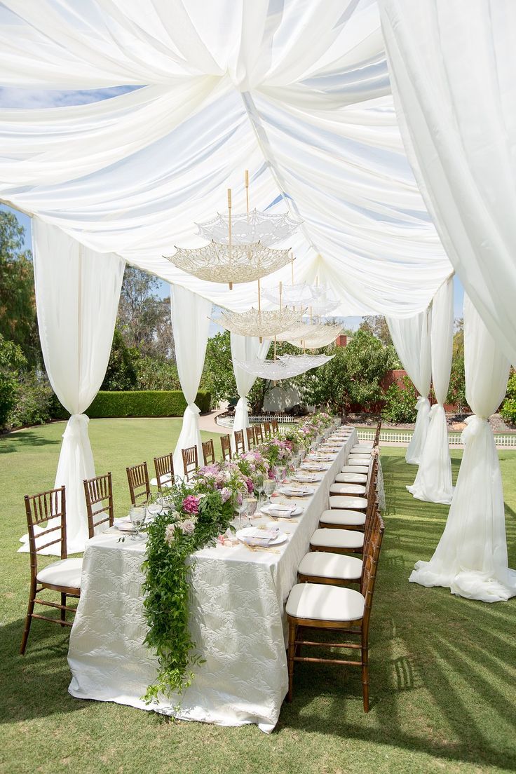 an outdoor wedding setup with white draping and greenery