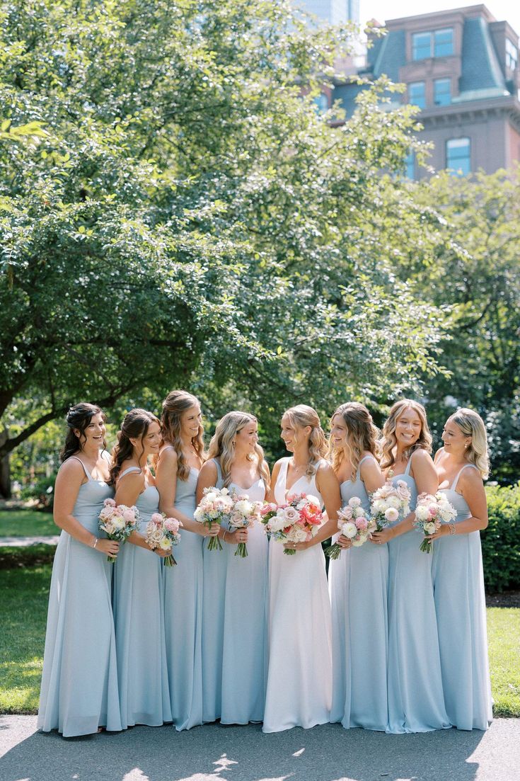 a group of women standing next to each other in front of some trees and buildings