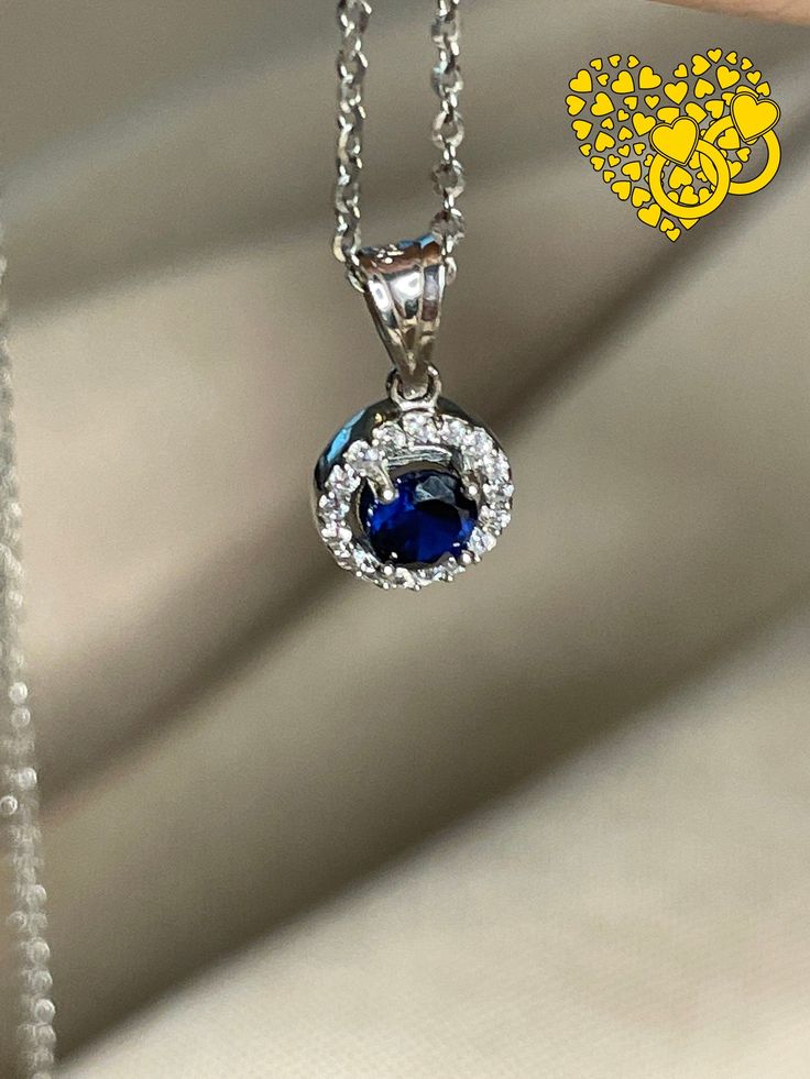 One Carat Round Cut Natural Blue Sapphire Necklace with halo diamonds necklace The depth and richness of the blue in this sapphire is reminiscent of velvet. Safely ensconced in a dazzling halo of pave diamonds (.50 carats-worth), this one-carat blue sapphire is absolutely dripping in elegance. This stunning necklace easily goes from the office to a romantic night in the town without missing a beat. In addition to ensuring a fabulous September birthday, this piece also doubles as a delightful 45t Luxury Round Sapphire Diamond Necklace, Formal Blue Diamond Necklace, Formal Sapphire Diamond Necklace With Brilliant Cut, Formal Sapphire Pendant Diamond Necklace, Formal Blue Diamond Gemstone Necklace, Formal Blue Gemstone Diamond Necklace, Formal Round Sapphire Necklaces, Luxury Blue Diamond Necklace For Anniversary, Blue Luxury Diamond Necklace For Anniversary