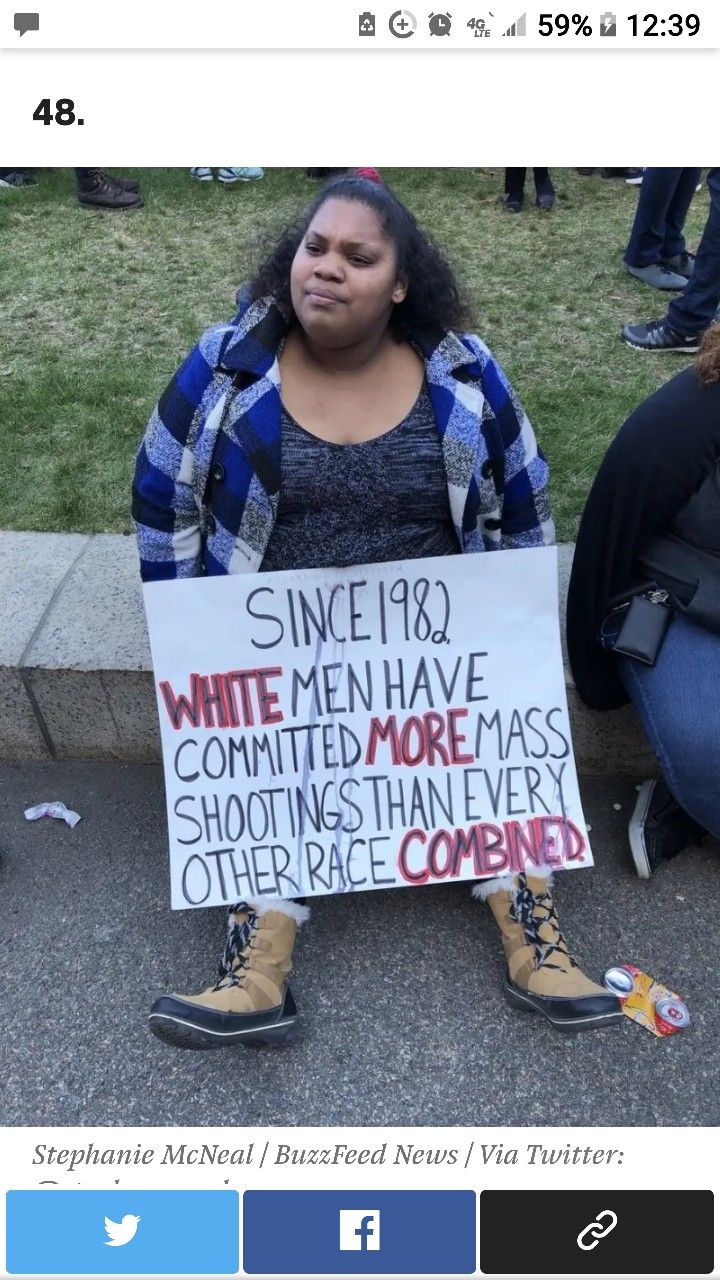 a woman sitting on the ground holding a sign