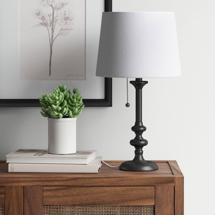 a table with a lamp on top of it and a plant in a pot next to it