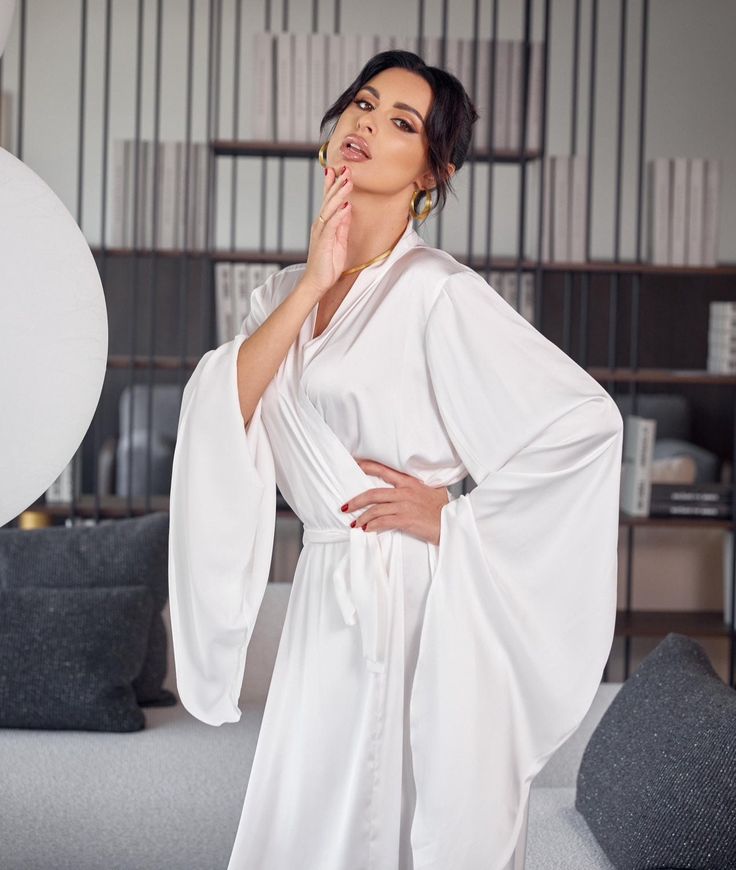 a woman in white is posing with her hands on her chin and looking up at the ceiling