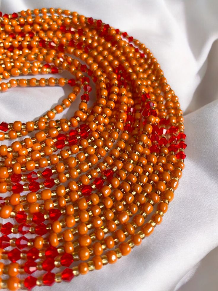 "Oupoyo" – a Single Strand Waist Bead that brings together the rich warmth of orange crystal glass seed beads and the subtle opulence of gold glass seed bead accents. ✨ Vibrant Orange Radiance: Oupoyo exudes a radiant glow with its vibrant orange crystal glass seed beads, reflecting the energy of the sun and infusing your ensemble with a lively and spirited charm. 🌟 Gold Opulence: Interspersed among the beads are golden accents, evoking a sense of opulence and sophistication. The gold glass see Orange Bohemian Beaded Bracelets With Faceted Beads, Oval Beaded Waist Beads For Gifts, Traditional Orange Beads For Gifts, Orange Faceted Beaded Bracelets, Orange Faceted Round Beaded Bracelets, Orange Jewelry With Gold Beads For Gift, Orange Gold Beaded Jewelry For Gift, Adjustable Orange Spacer Beads, Traditional Orange Beaded Bracelets With Polished Beads