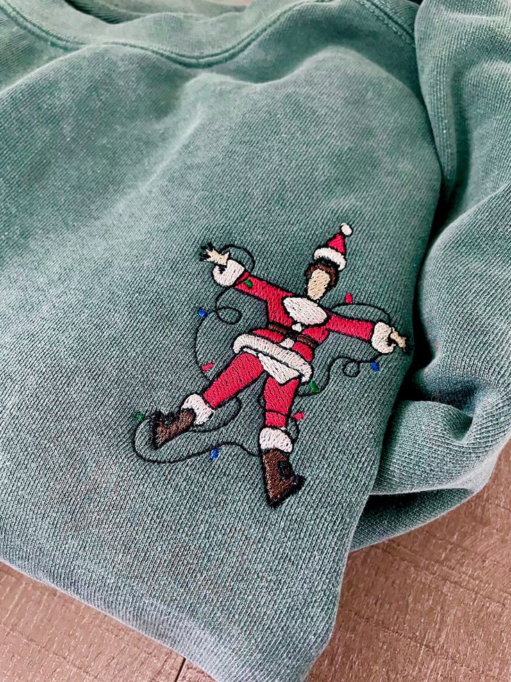 Get ready to spread some electrifying holiday cheer with our side-splittingly funny embroidered sweatshirt featuring Santa Claus in a shocking situation! This whimsical design captures the moment when Santa accidentally gets entangled in a tangle of mischievous Christmas lights, resulting in a hilarious jolt of laughter for everyone around. Key Features: 1. Premium Quality: Crafted with the finest soft and cozy fabric, this holiday sweatshirt ensures maximum comfort and durability, making it perfect for those chilly winter nights. 2. Electrifying Embroidery: The expertly embroidered design showcases Santa Claus in a hilarious predicament, surrounded by vibrant and detailed Christmas lights that radiate humor. 3. Unisex Sizing: Available in a range of sizes, this sweatshirt is designed to f Casual Christmas Sweatshirt With Custom Embroidery, Embroidered Long Sleeve Christmas Sweatshirt, Embroidered Christmas Holiday Sweatshirt, Christmas Holiday Embroidered Sweatshirt, Holiday Embroidered Crew Neck Sweatshirt, Embroidered Crew Neck Sweatshirt For Holiday, Christmas Crew Neck Sweatshirt With Embroidered Graphics, Christmas Embroidered Crew Neck Sweatshirt, Christmas Embroidery Sweater