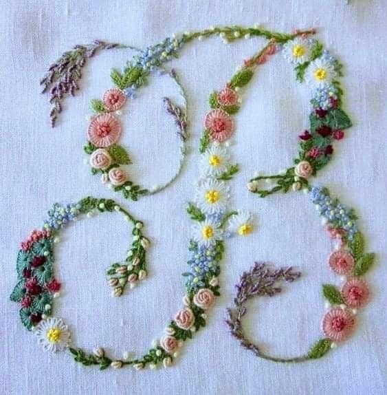 some flowers and leaves are on a white table cloth with scissors, thread and beads