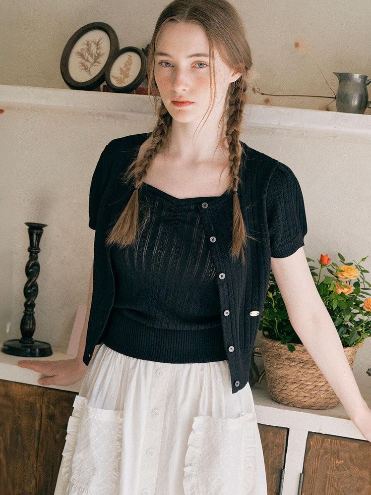 a woman with braids standing in front of a shelf and looking at the camera