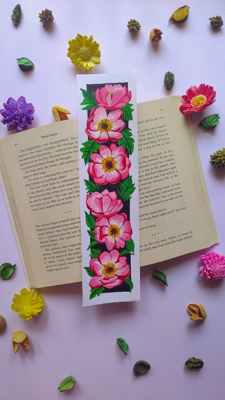 an open book with flowers and leaves on it