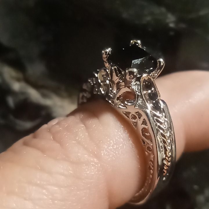 a close up of a person's hand with a ring on their finger that has a black diamond in it