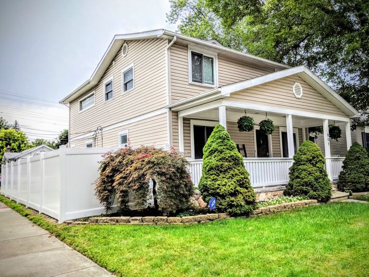 a house with white picket fence in front of it and green grass on the lawn