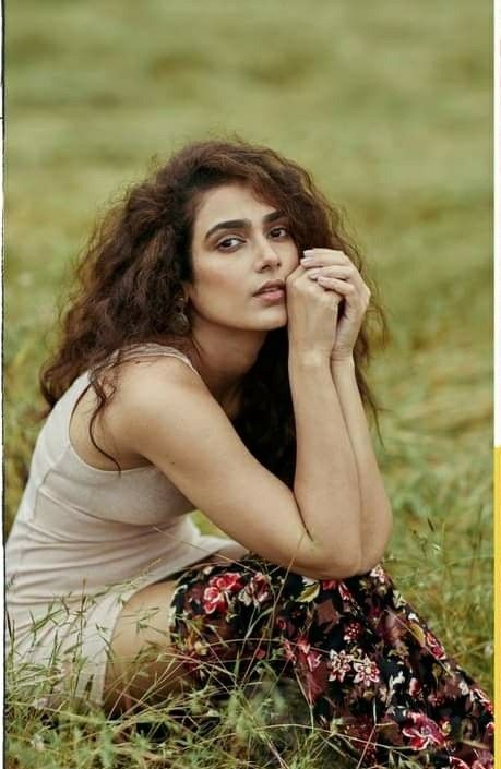 a woman sitting in the grass with her hand on her chin