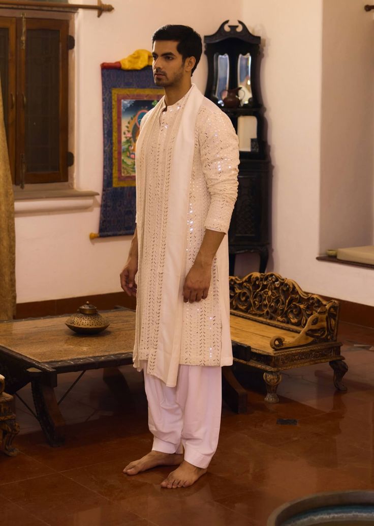 The umaid kurta in ivory is a sophisticated choice for Indian grooms, perfect for haldi, mehndi, or sangeet ceremonies. Crafted from a blend of viscose cotton silk and georgette, this kurta offers a soft, breathable feel that’s ideal for festive occasions. This kurta comes with a matching ivory salwar, creating a seamless and cohesive ensemble. Whether you're attending a traditional ceremony or a contemporary event, the umaid kurta is a versatile and elegant choice. Salwar Pattern, Indian Groom, Embroidered Border, Luxury Sale, Bespoke Tailoring, Thread Embroidery, Band Collar, Kurta Set, Embroidered Silk