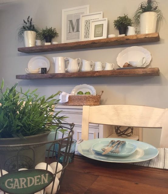 a dining room table with plates and bowls on it, two shelves above the table