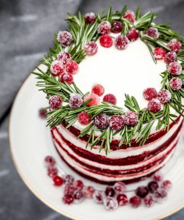 a christmas cake decorated with cranberries and greenery on a plate stock photo