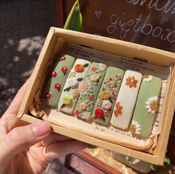 an open box that has some kind of decorated cookies in it with flowers on them