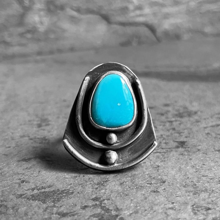 Sleeping Beauty Turquoise and Sterling Silver ᏎᎷ Selu Corn Ring Natural, backed, sky ᏌᎪᏂᎨᎢ sakonige blue  Turquoise from the Sleeping Beauty mine in Arizona graces this stylized ᎠᏕᎸ ᎤᏁᎬ adelv unegv Sterling Silver ᏎᎷ Selu Corn ring. It's a petite sized band, a US 5.5, that packs quite the punch and makes quite the statement.  * ᏅᏯ nvya Stone: Turquoise, natural, unbacked, from Arizona, Color: sky ᏌᎪᏂᎨᎢ sakonige ᏌᎪᏂᎨᎢ sakonige blue with one tiny spot of ᎤᏁᎦ unega white host rock showing (not a chip in the stone, see photos please), Shape: Teardrop, Size: length 13 mm, width 11 mm, height 3 mm * Metal: Bezel is fine silver, all the rest is ᎠᏕᎸ ᎤᏁᎬ adelv unegv Sterling Silver. * Finish: shiny * Size: US 5.5  * Dimensions: length 1", width .88", height (of part on top of band) .19" * Design: Ꮞ Natural Sleep, Sleeping Beauty Turquoise, Blue Turquoise, Turquoise Sterling Silver, Fine Silver, Turquoise Blue, Statement Ring, Rings Statement, Sky Blue