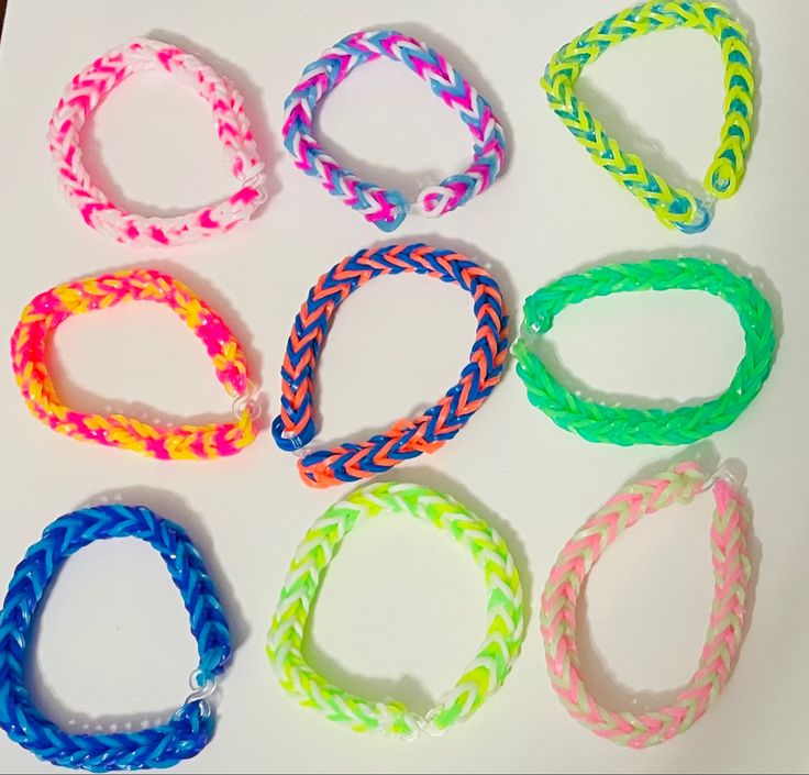 six different colored bracelets sitting on top of a white table next to each other