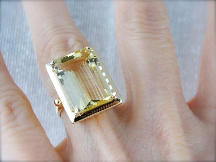 Like the first rays of a summer dawn, this ring is all about the light - clean and clear hues of the palest possible yellow. This buttery gem is Scapolite; a lovely gemstone often confused with a Citrine or Yellow Beryl. Perfectly balanced in a vintage gold cocktail ring setting, this piece is sure to make a gorgeous and unique ring for any occasion! Metal: 14K Yellow Gold Gem: Scapolite 13.10 Carats Gem Measurements: 13 x 17 mm, Rectangle Emerald Cut Ring Size: 6 Marks: "14K" Stamped on the ins Timeless Yellow Gemstone Jewelry, Elegant Yellow Faceted Gemstones, Yellow Gemstone Ring With Rectangular Stone, Yellow Rings With Gemstone And Rectangular Stone, Rectangular Yellow Gemstone Jewelry, Yellow Rectangular Gemstone Jewelry, Gem Rings, Emerald Cut Ring, Vintage Cocktail Ring