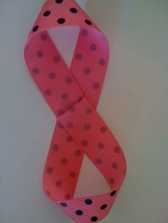 a pink and black polka dot ribbon hanging on a wall