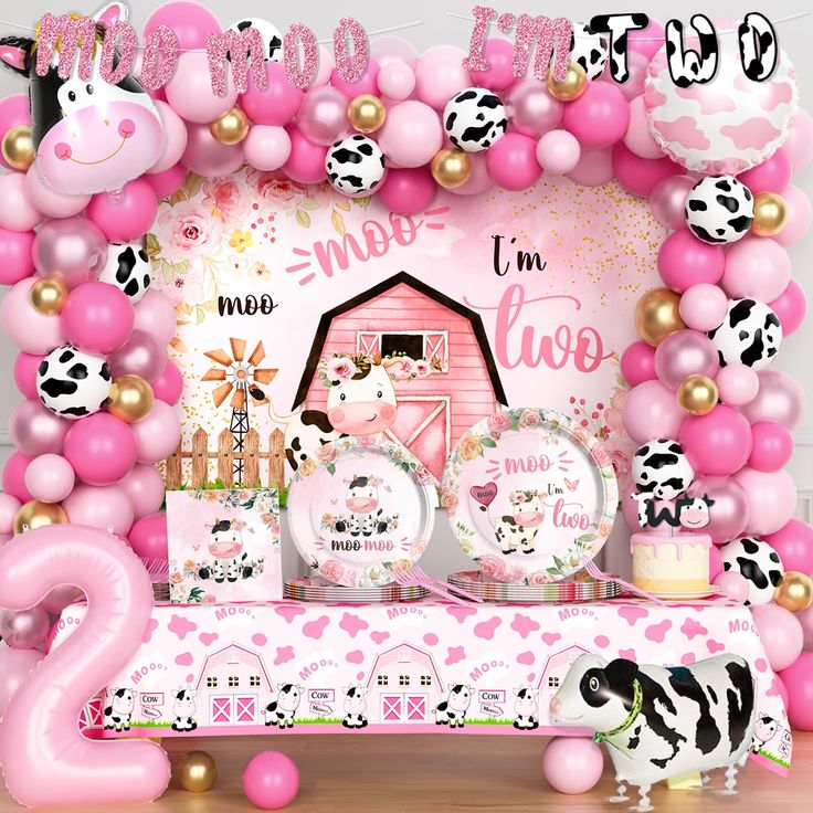 a pink and black cow themed birthday party with balloons, plates, cups, and decorations