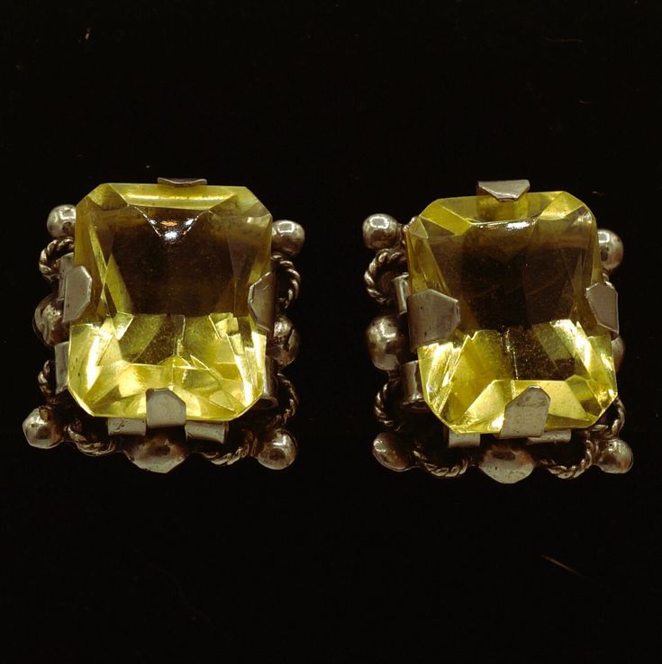 These are handcrafted 1950s Vintage large faceted rectangular (emerald shape) yellow Citrine gemstone post screw back earrings.   The stones sit upon handcrafted shaped silver barrels haloed by silver rope and circle designs. Hallmarked Silver Mexico. They are in great vintage shape for their age with a few scratches on each gemstone. See photos.  Silver has patina so I would recommend a professional polish. Silver tests 800-925   Stone has tested Citrine on Presidium Gem Tester II. 1st Citrine Measures approximately:  15.22 mm x 12.04 mm x 5.40+ mm 2nd Citrine Measures approximately:  14.86 mm x 11.97 mm 5.60+ mm Earrings weighs:  .343 ounces Free Shipping Vintage Amber Rectangular Jewelry, Yellow Rectangular Stone Jewelry For Formal Occasions, Yellow Rectangular Citrine Jewelry, Yellow Rectangular Gemstone Jewelry, Rectangular Yellow Gemstone Jewelry, Handmade Yellow Rectangular Jewelry, Antique Faceted Silver Jewelry, Vintage Jewelry With Gold Rectangular Stone, Vintage Citrine Gemstone Jewelry