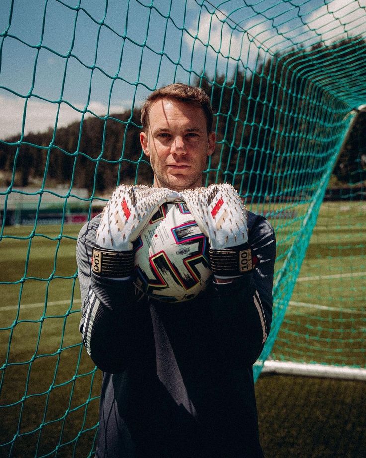 a man is holding a soccer ball in front of a goalie's net