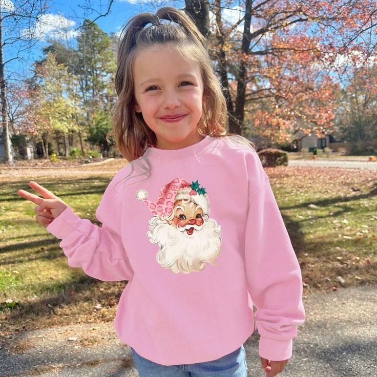 This cozy crewneck is the perfect gift for a girl or woman. Featuring the cute pink santa with leopard print hat, this shirt is stylish and cute winter wear. 𝐇𝐎𝐖 𝐓𝐎 𝐎𝐑𝐃𝐄𝐑 1. Select the size & color when applicable 2. Add the personalization (name, design etc) when required 3. Add to Cart & submit your order. 4. If ordered over $35, we have FREE shipping for you! 𝐀𝐋𝐖𝐀𝐘𝐒 𝐇𝐀𝐍𝐃𝐌𝐀𝐃𝐄 * Each item is handmade and made to order here in Florida! * We carry several different brands and use different brands for different listings, including Rabbit Skins®, Gildan®, Gerber Onesie®, Bella Canvas® and Comfort Colors®. G A R M E N T ∙ F E A T U R E S : * Unisex Fit * Commercial grade heat press S H I P P I N G * All items get sent via USPS first class mail * Priority 2-3 day shippin Pink Letter Print Top For Winter, Winter Pink Top With Letter Print, Pink Tops With Letter Print For Winter, Christmas Long Sleeve Tops With Cartoon Print, Trendy Winter Tops With Cartoon Print, Long Sleeve Cartoon Print T-shirt For Winter, Cute Winter Graphic Print Top, Pink Cotton Holiday Sweatshirt, Pink Cotton Christmas Tops