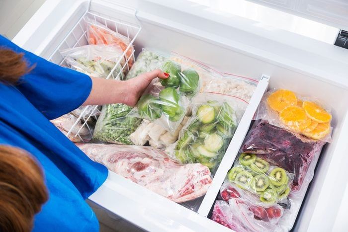 a person reaching into an open refrigerator with food in it