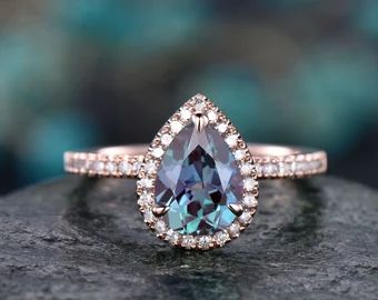 an engagement ring with a pear shaped blue topazte surrounded by small white diamonds