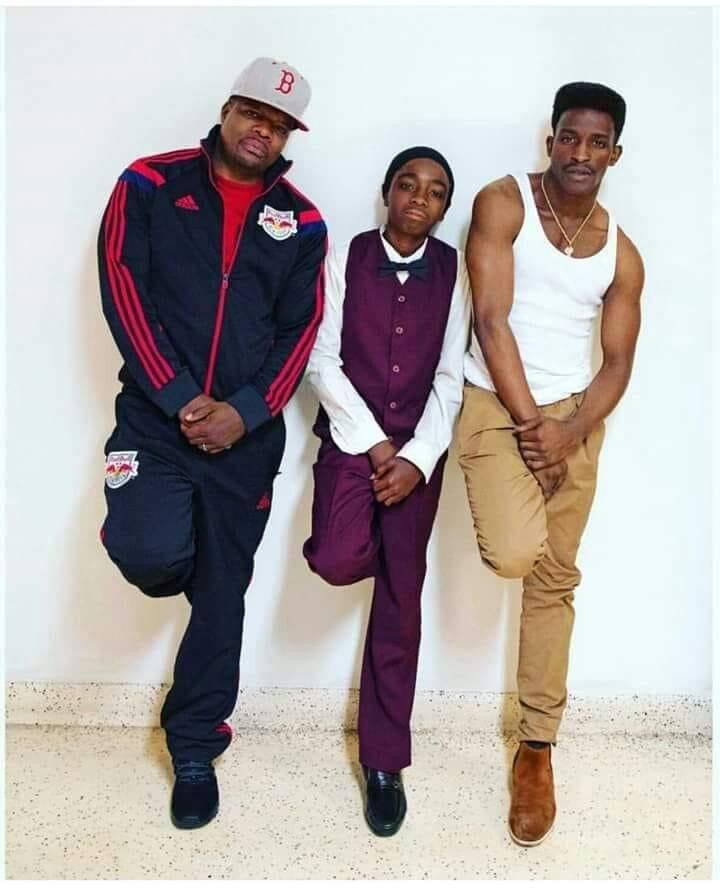 three men are posing for the camera in front of a white wall wearing matching clothing