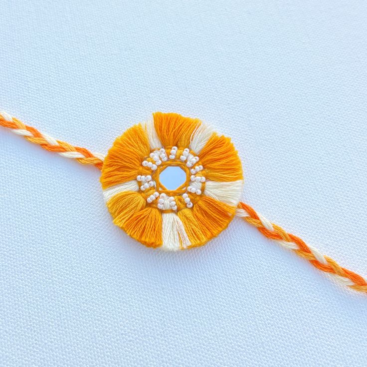 an orange and white tasseled piece with beads on it sitting on a blue surface