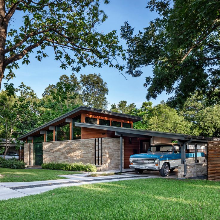 a blue truck parked in front of a house next to a lush green yard and trees