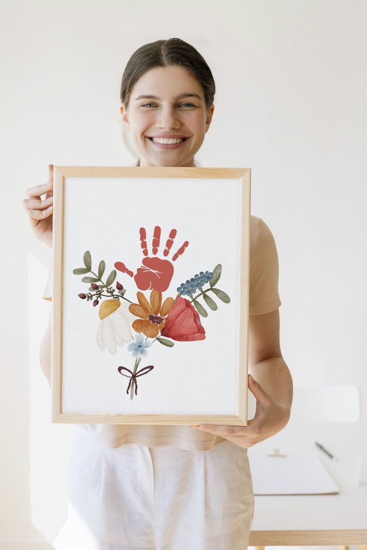 a woman holding up a painting with flowers on it