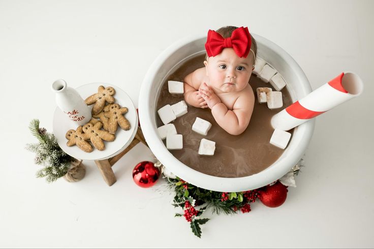 a baby in a bathtub with marshmallows and christmas decorations around it