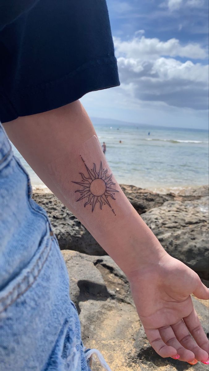 a woman's arm with a small sun tattoo on the left side of her wrist