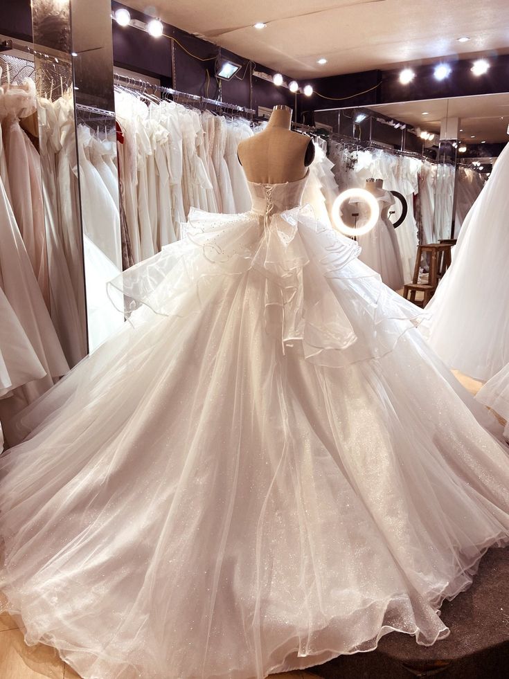 a wedding dress is displayed in front of a mirror and mannequins are behind it