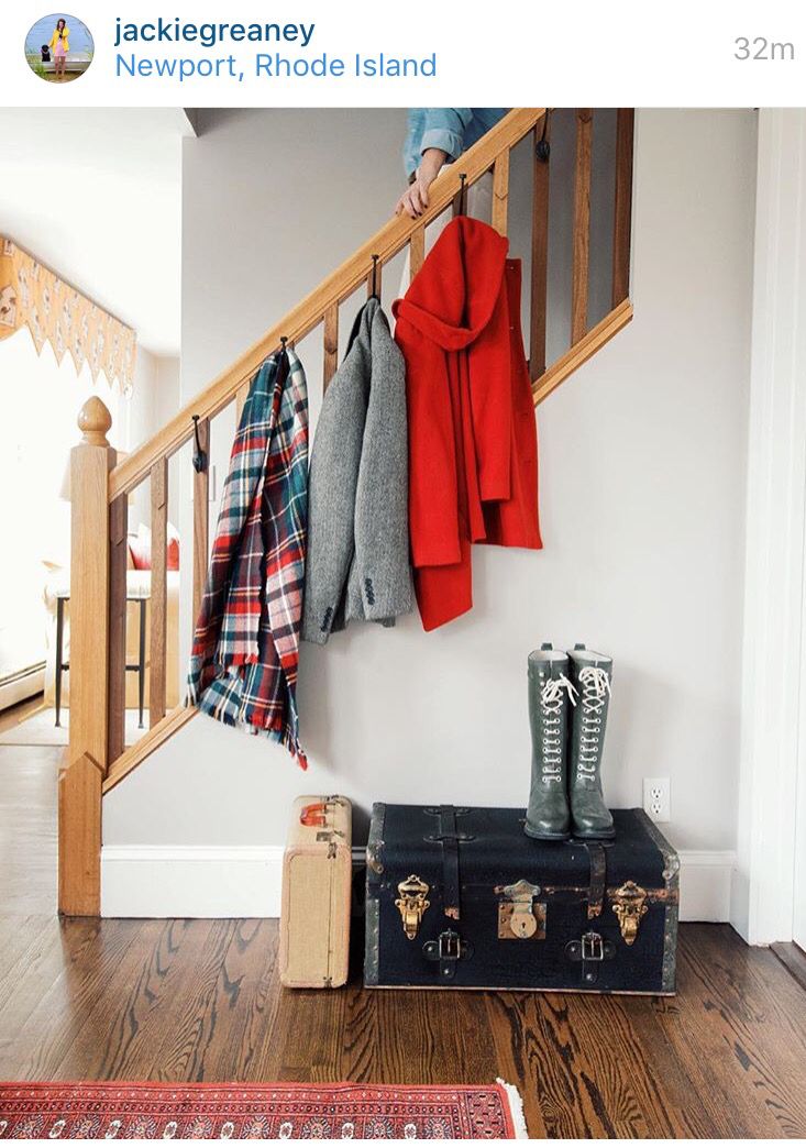 there is a suitcase and coat rack on the floor next to a stair case with coats hanging from it