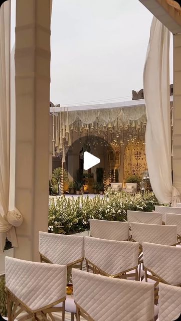 rows of white chairs sitting in front of a building with an arch over the entrance