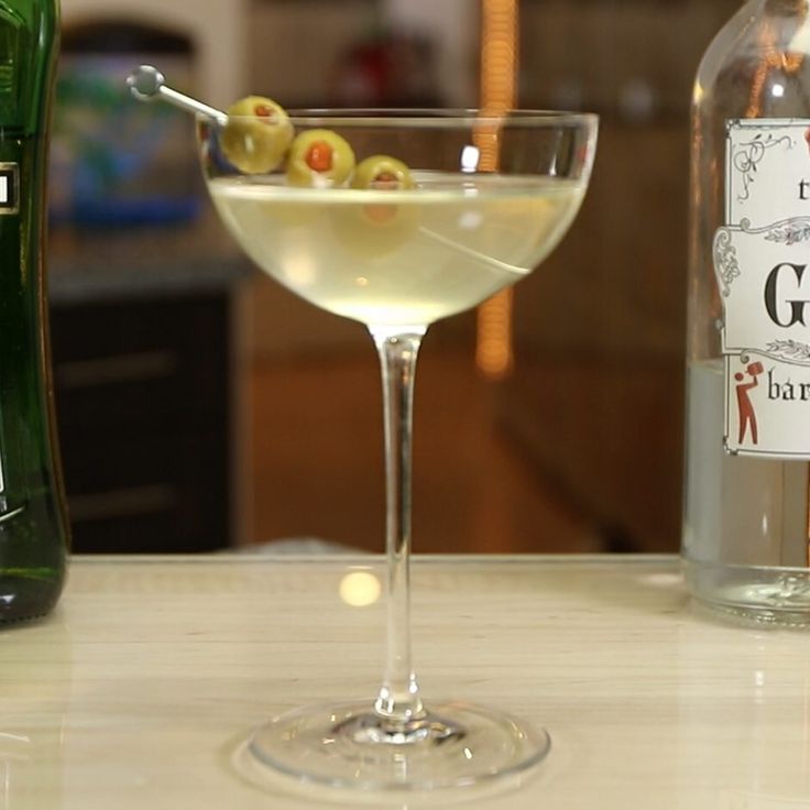 a martini with olives in it next to a bottle of gin