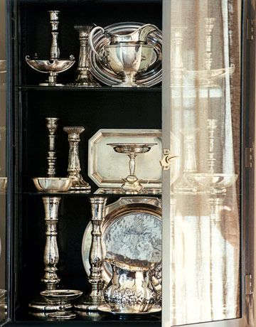 the shelves are filled with silver items and glass vases, including cups, dishes, and plates