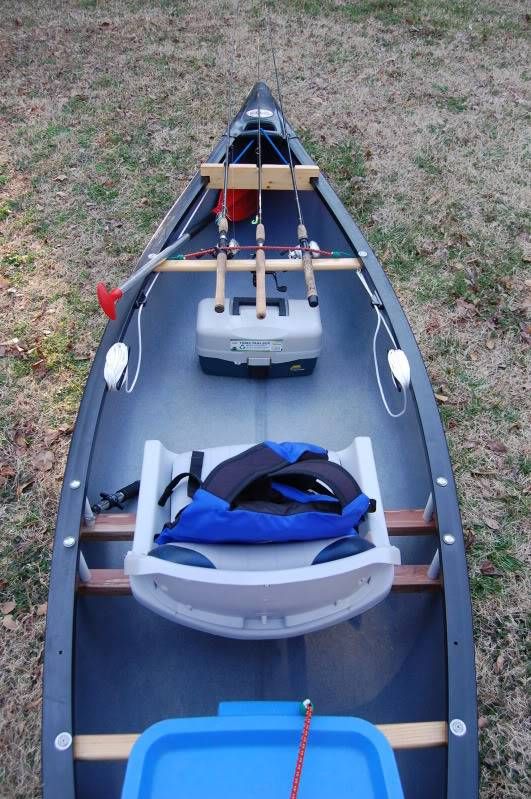 an empty canoe sitting in the grass with a life jacket on it's back