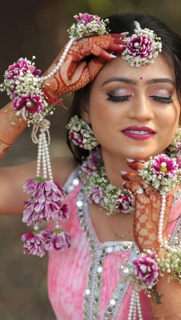 a woman in a pink dress holding her hands up to her head with flowers on it