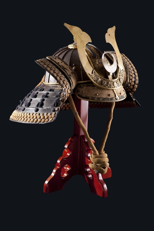 an old helmet is sitting on top of a stand with two swords in the middle