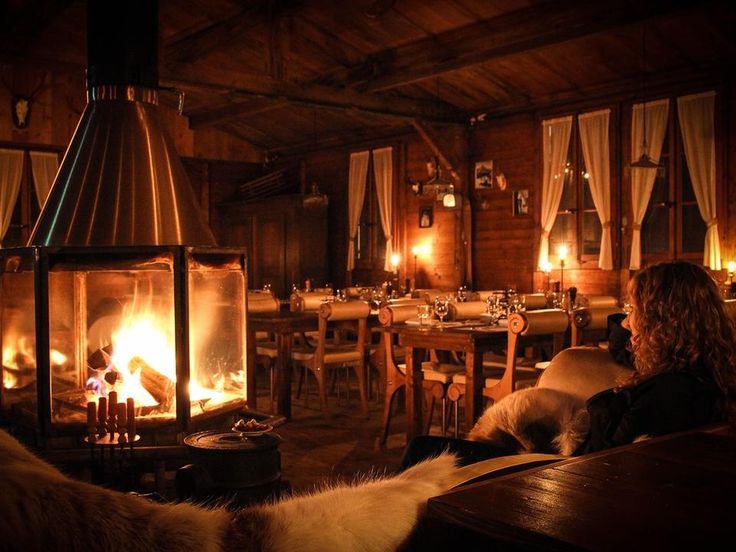 a woman sitting in front of a fire place with candles on it's sides